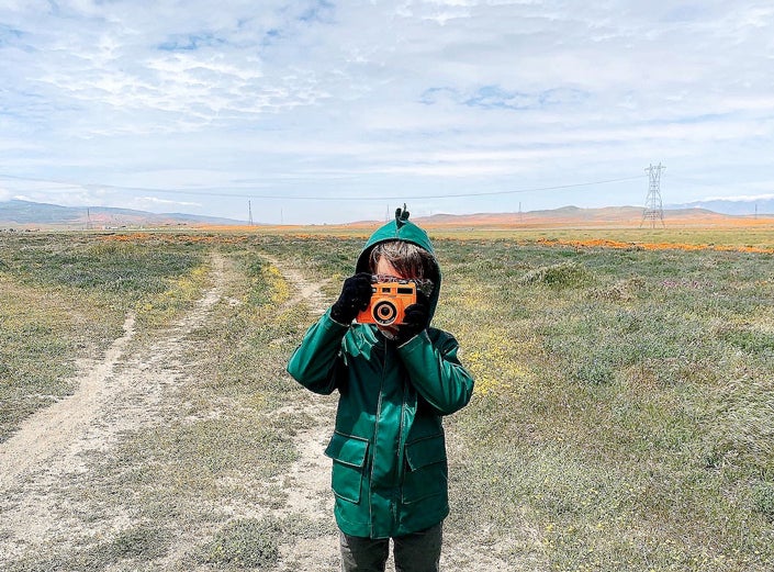 Little boy holding toy camera in wildflower field