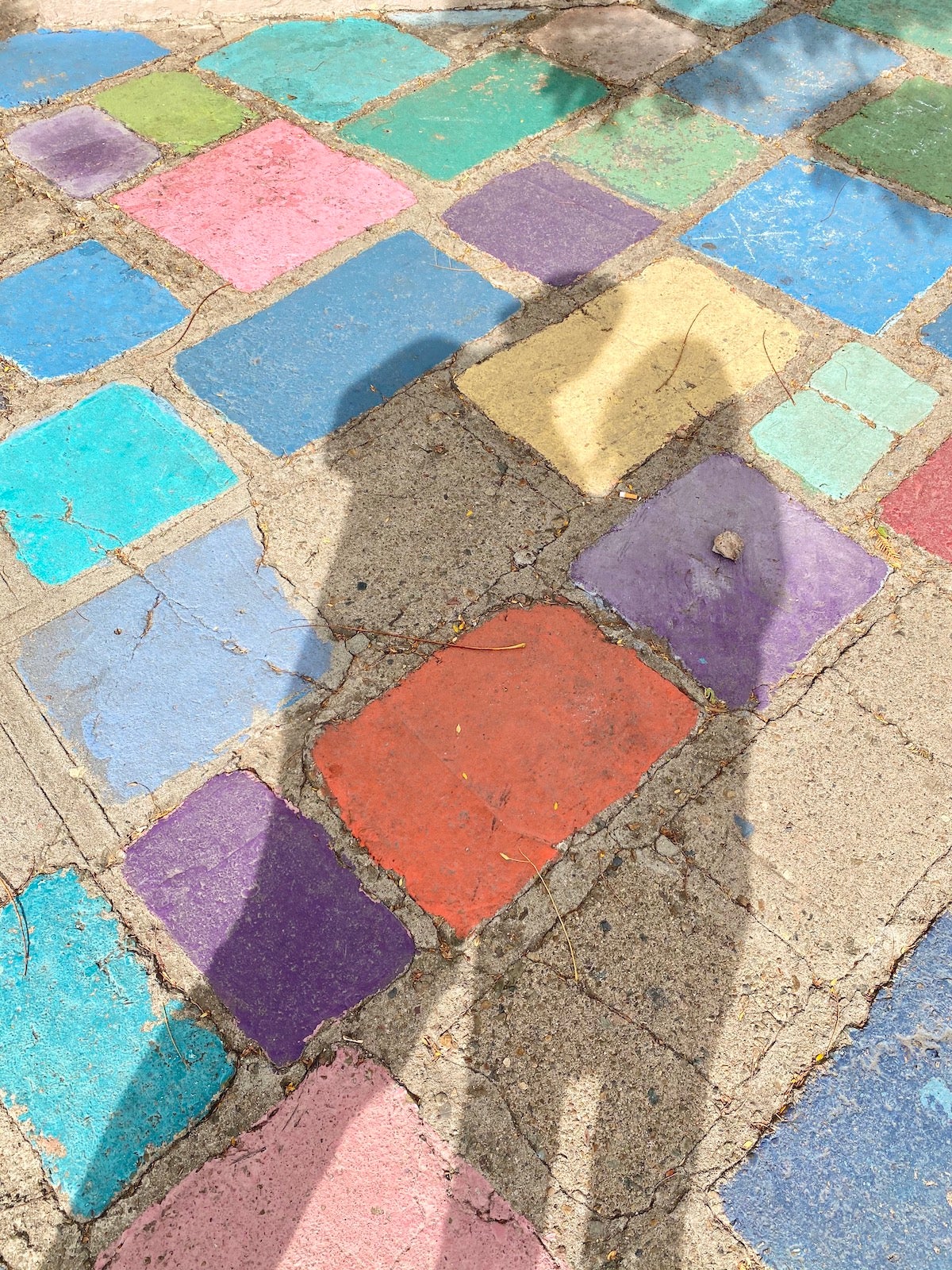 Shadows of the photographer displayed on a multi-colored cement tile floor