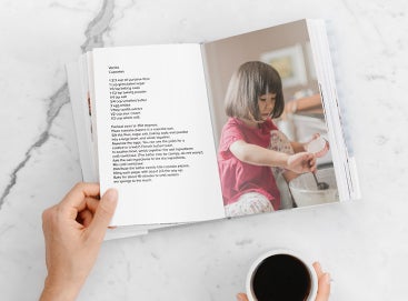 Recipe book opened to photo of little girl making cupcakes