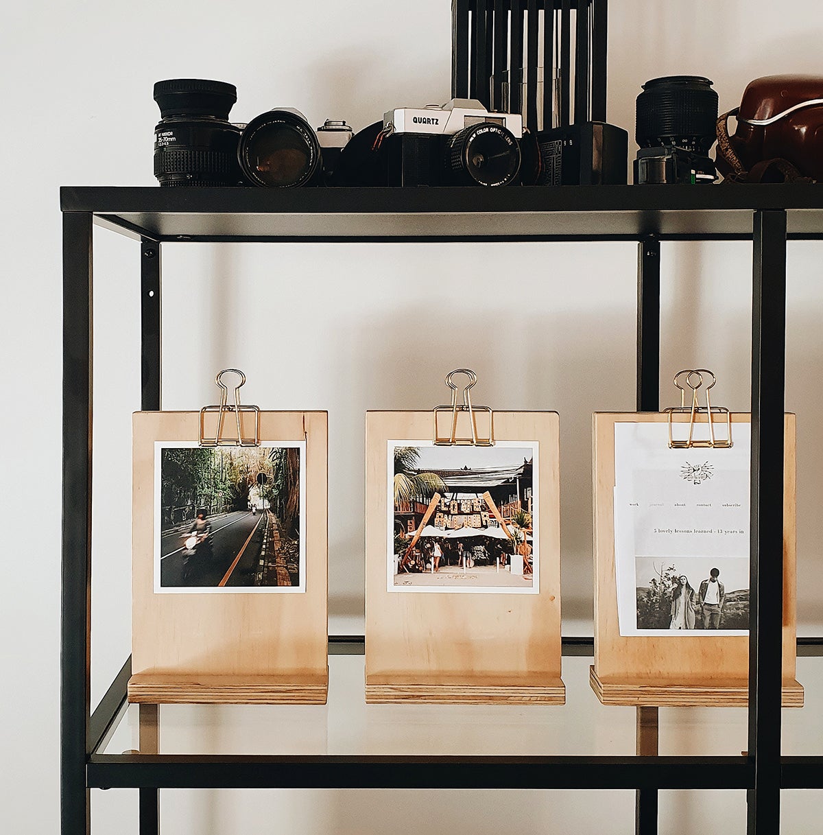 Unique wooden photo holders lined on a shelf and holding square prints