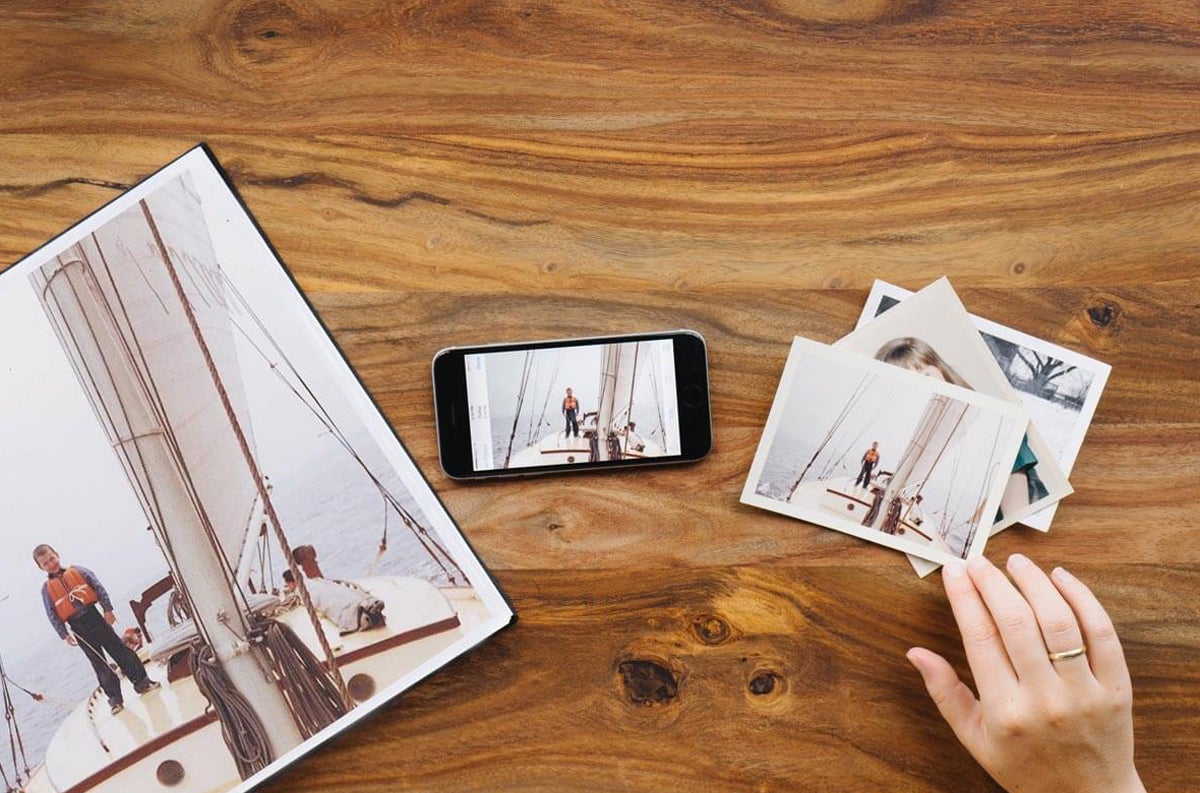 Old photo prints on table next to phone and framed photo