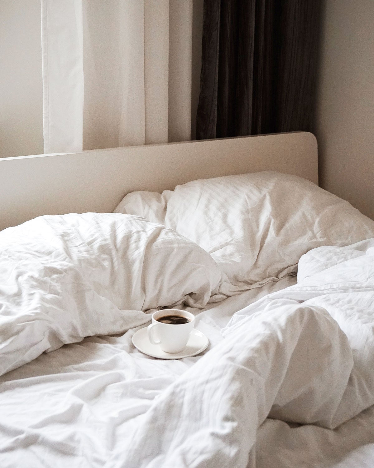 Cup of coffee in an empty unmade bed
