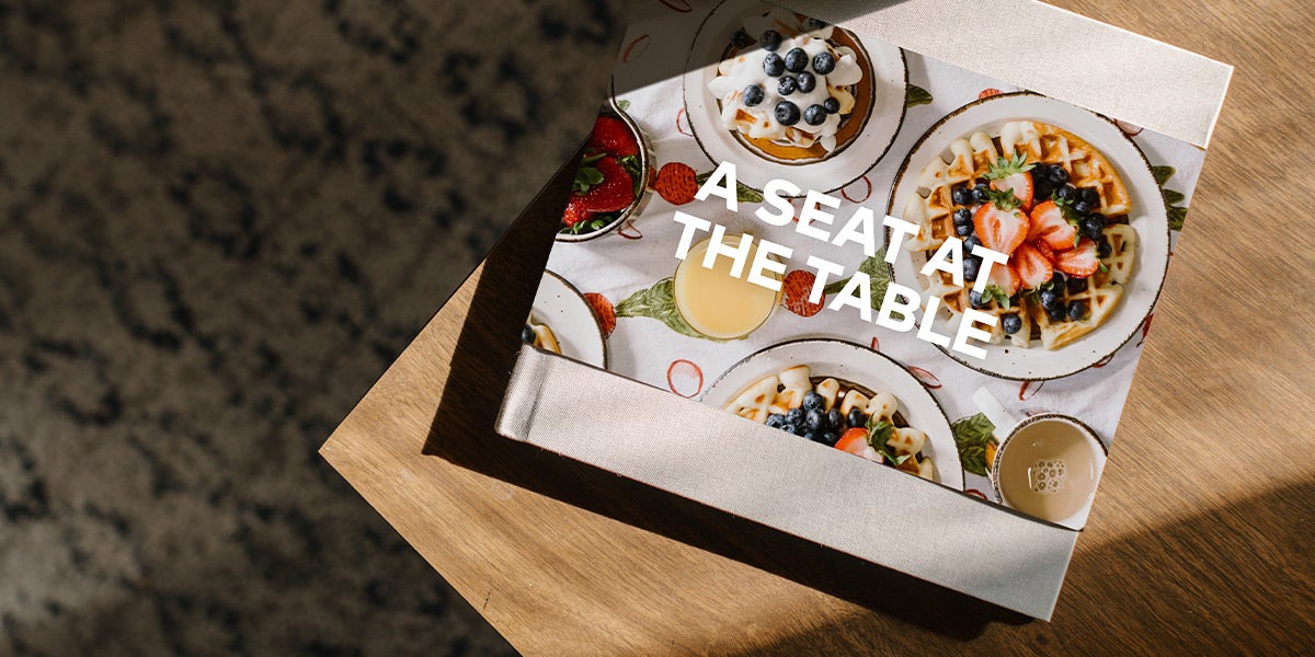 Collaborative cookbook titled A Seat at the Table with photos of waffles on cover