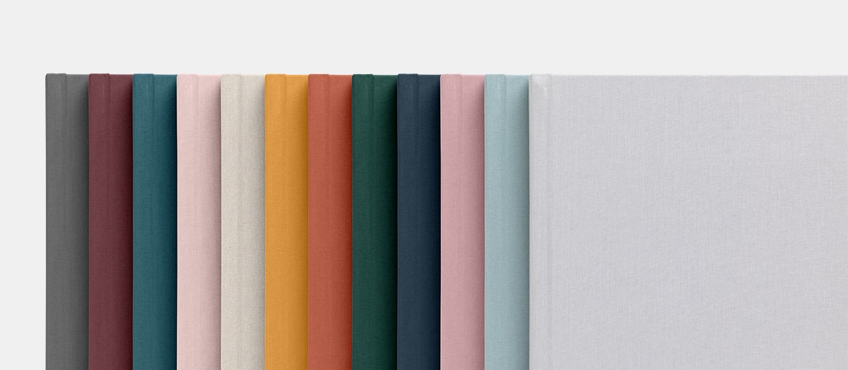 12 different colors of layflat albums laid out in color spectrum