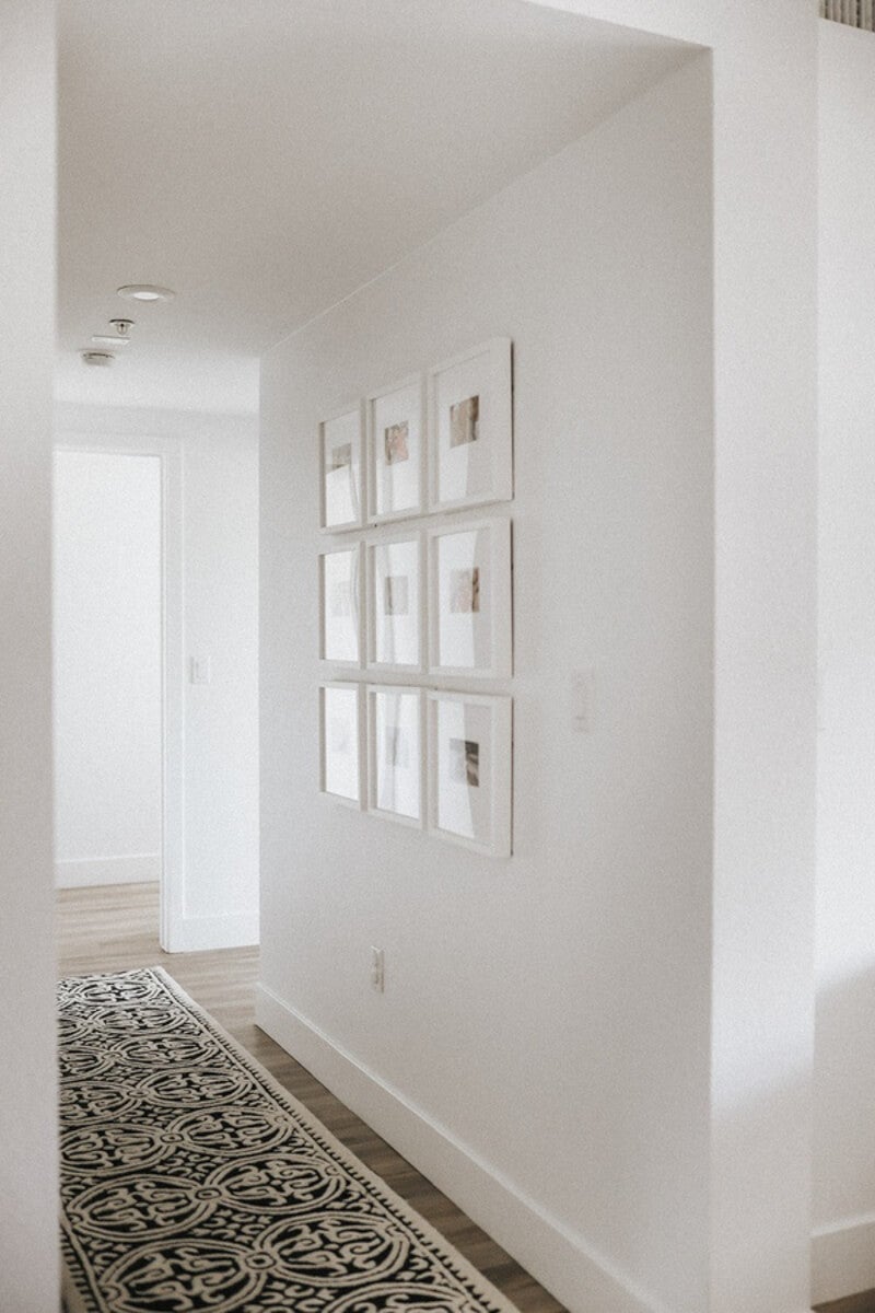 Gallery wall of family photos in brightly lit hallway