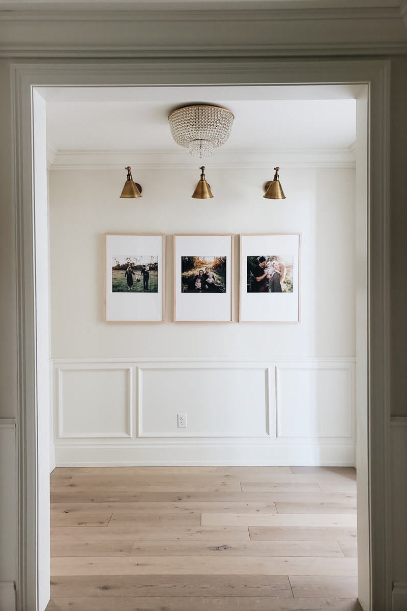 Three large framed family photos hung side by side in empty room