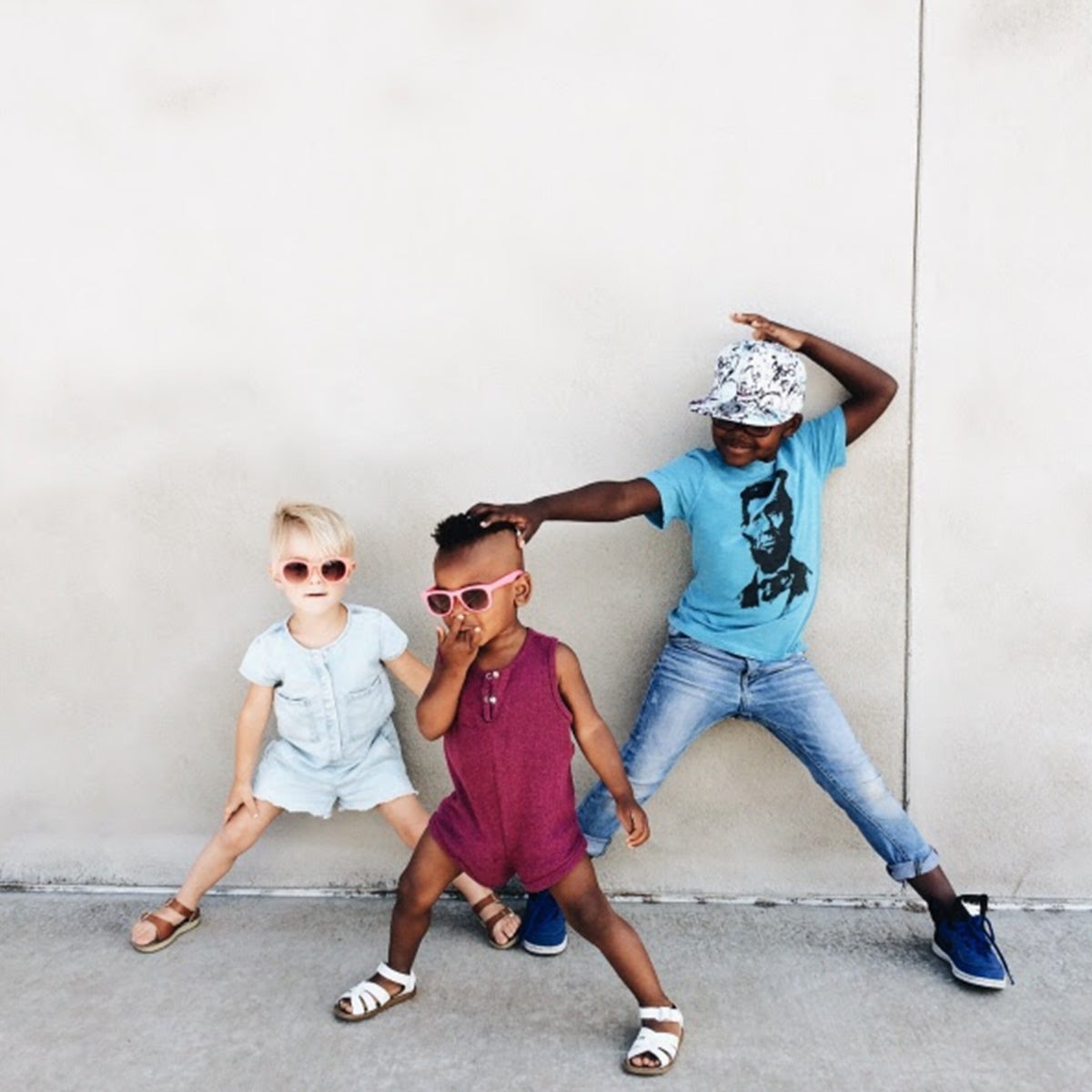 Trio of children in sunglasses striking dance poses