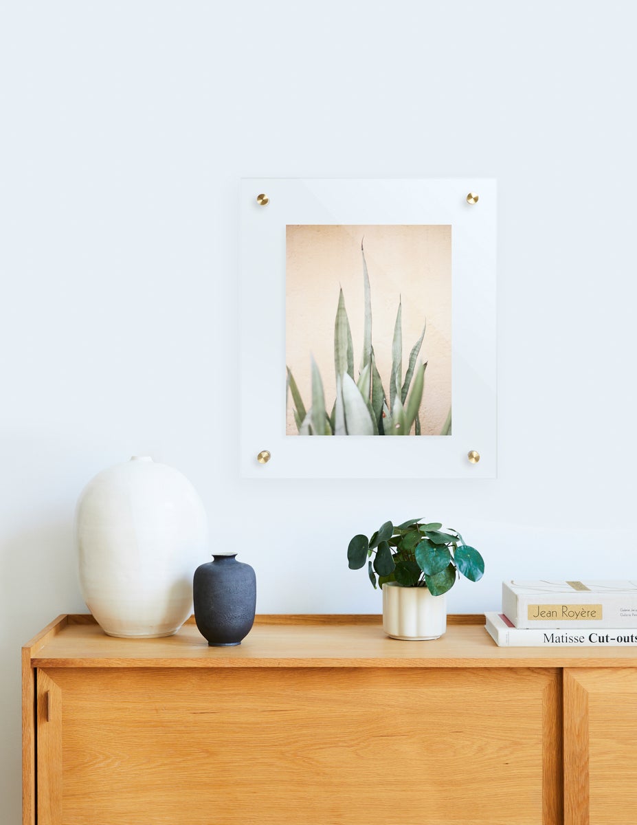 Artifact Uprising Floating Frame hanging above dresser with Pilea Peperomioides plant