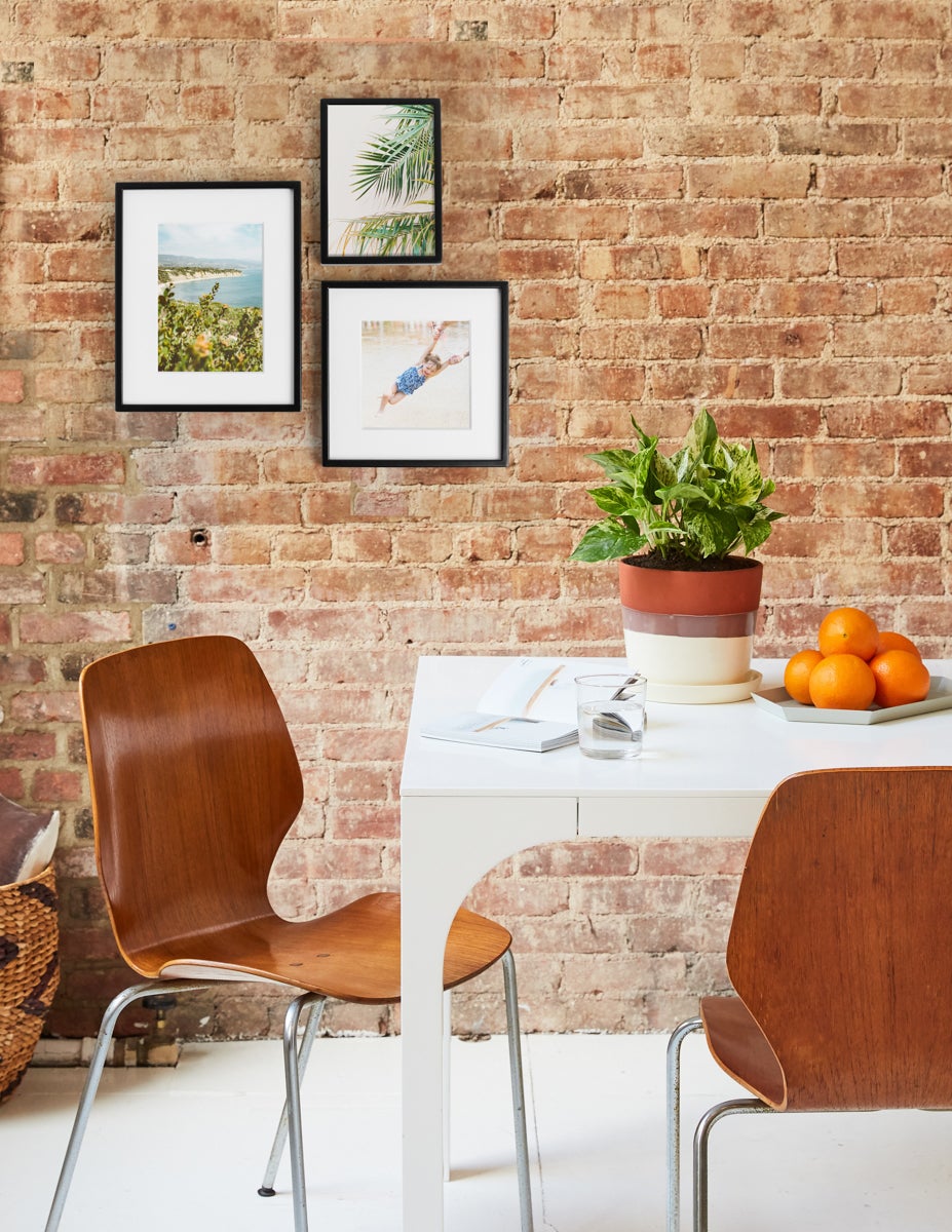 Golden Pothos on dining table with Metal Tabletop Frames hanging on the brick wall behind