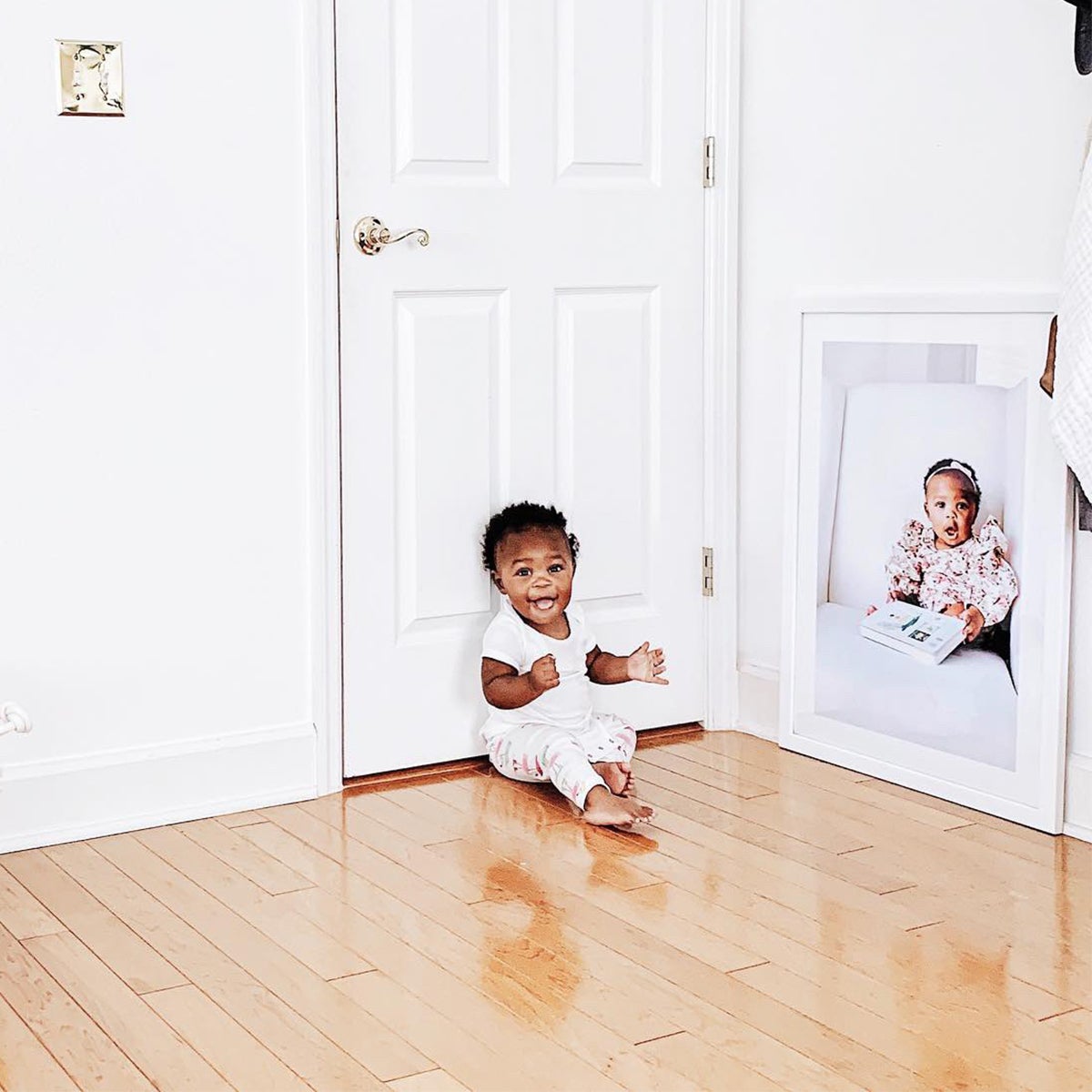 Baby sitting in front of enlarge photo of self resting on ground