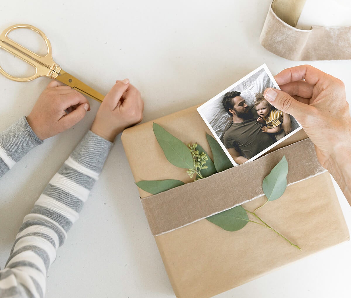 hands slipping photo print under ribbon of wrapped gift