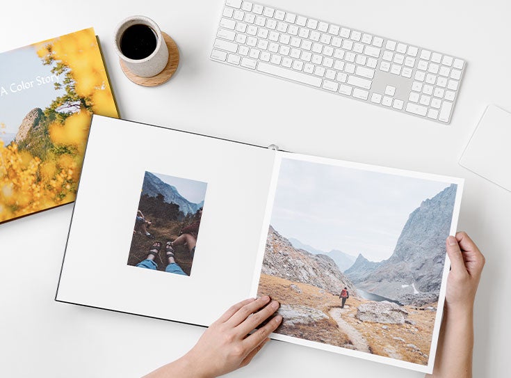 Photo book and coffee cup on desk next to keyboard