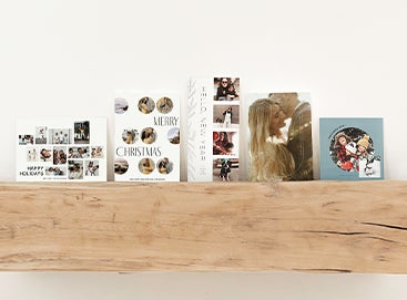 Five Artifact Uprising holiday photo cards lined side by side on a wooden mantel