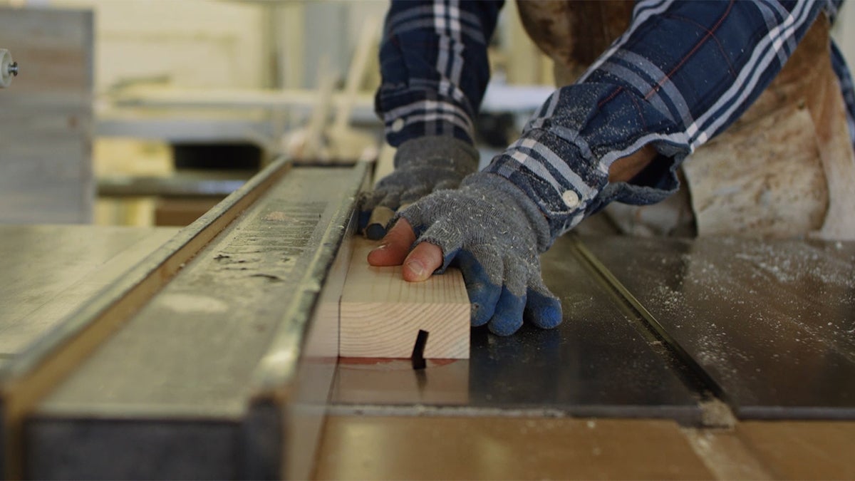 Hands cutting reclaimed wood on table saw