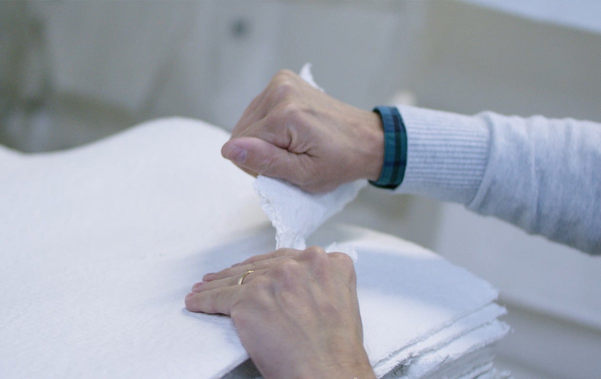 Hands tearing fiber used to make paper