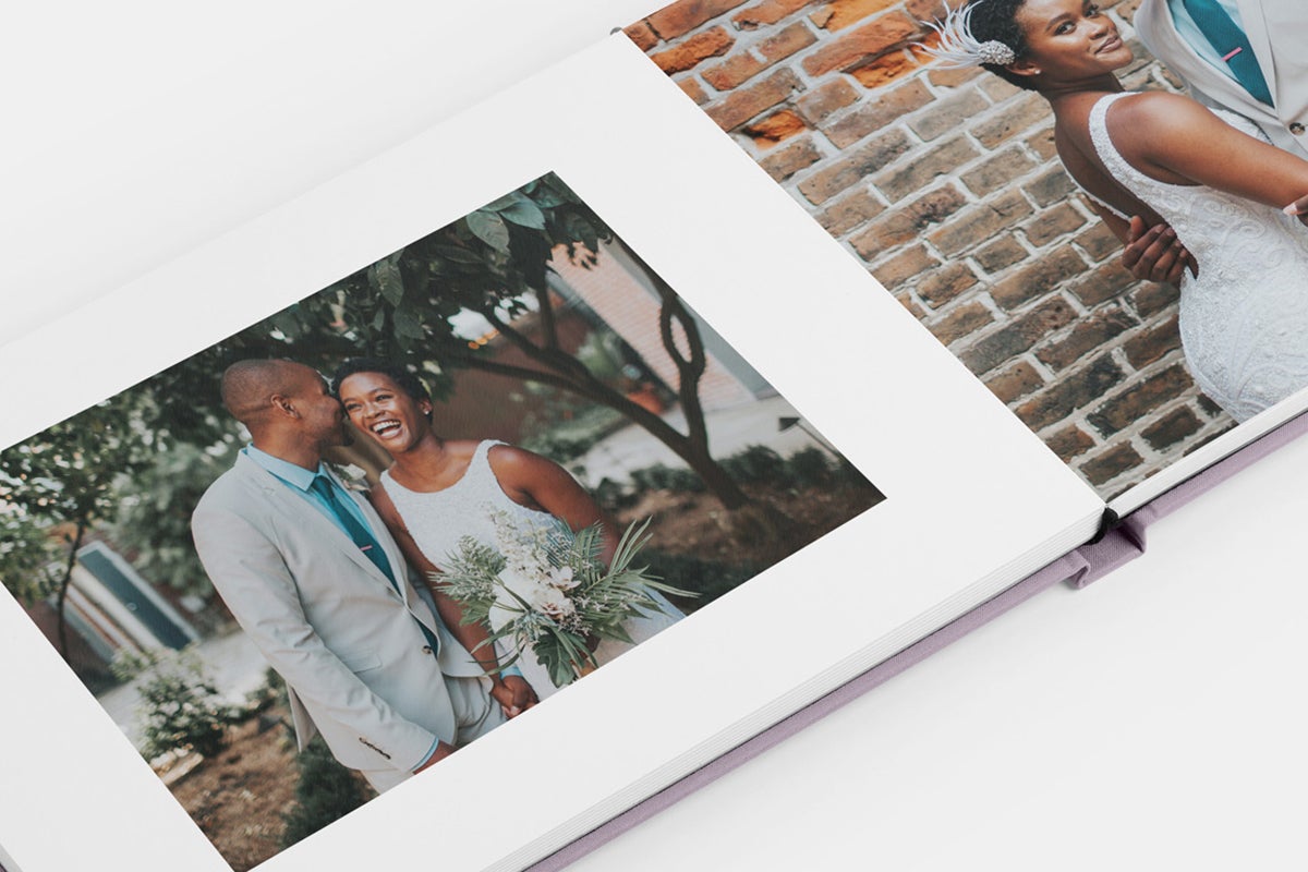 Image in photo book of bride and groom posing in front of textured brick wall