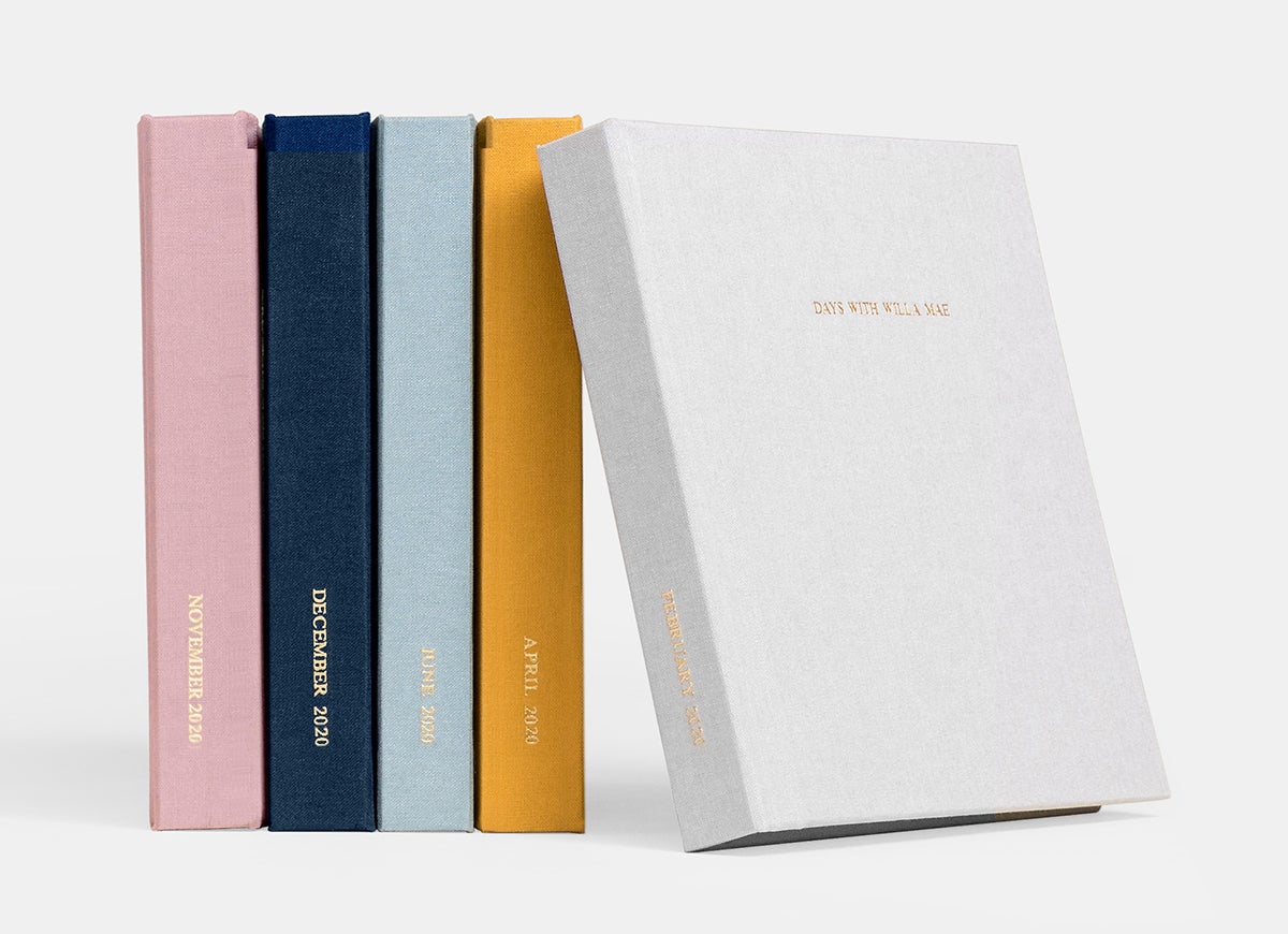 Four Everyday Photo Books in different colors lined up showing spines with fifth book flipped to show cover