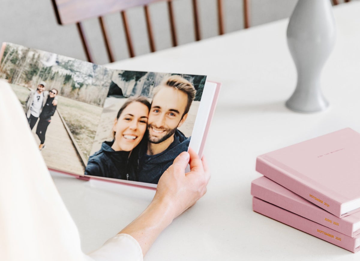 Woman holding an open, pink Everyday Photo Book filled with couple photos