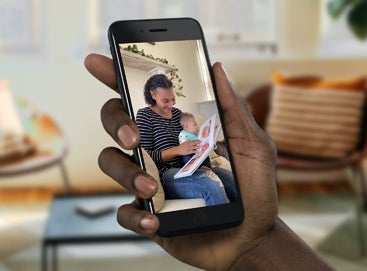 Hand holding phone for FaceTime with woman and child opening gift