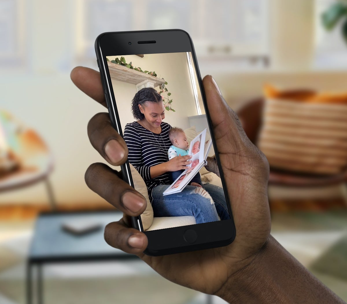 Hand holding phone for video chat with woman opening photo gift