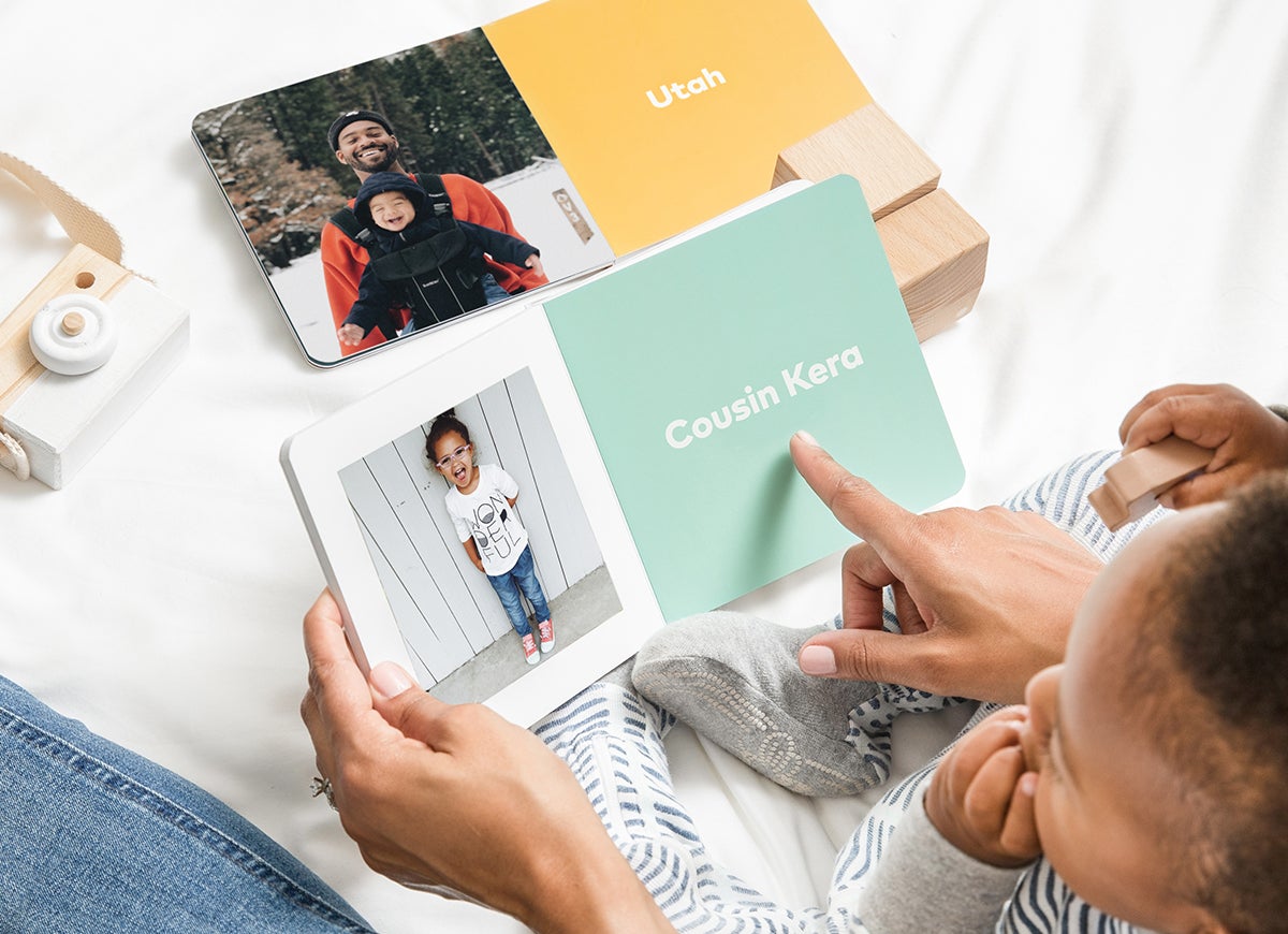 Mother and baby reading baby book filled with family members' photos and names