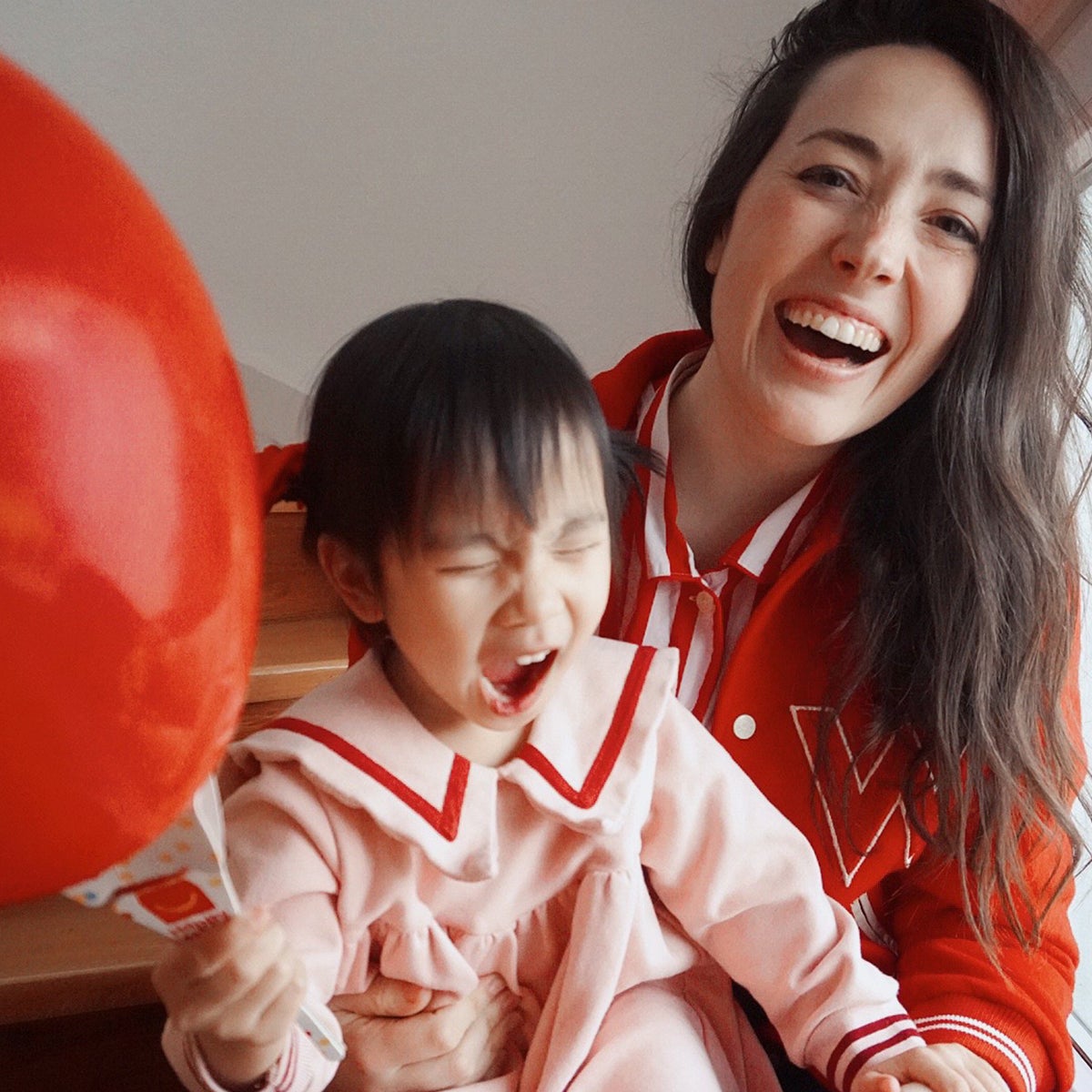 Photo of mother holding daughter who is holding a red baloon