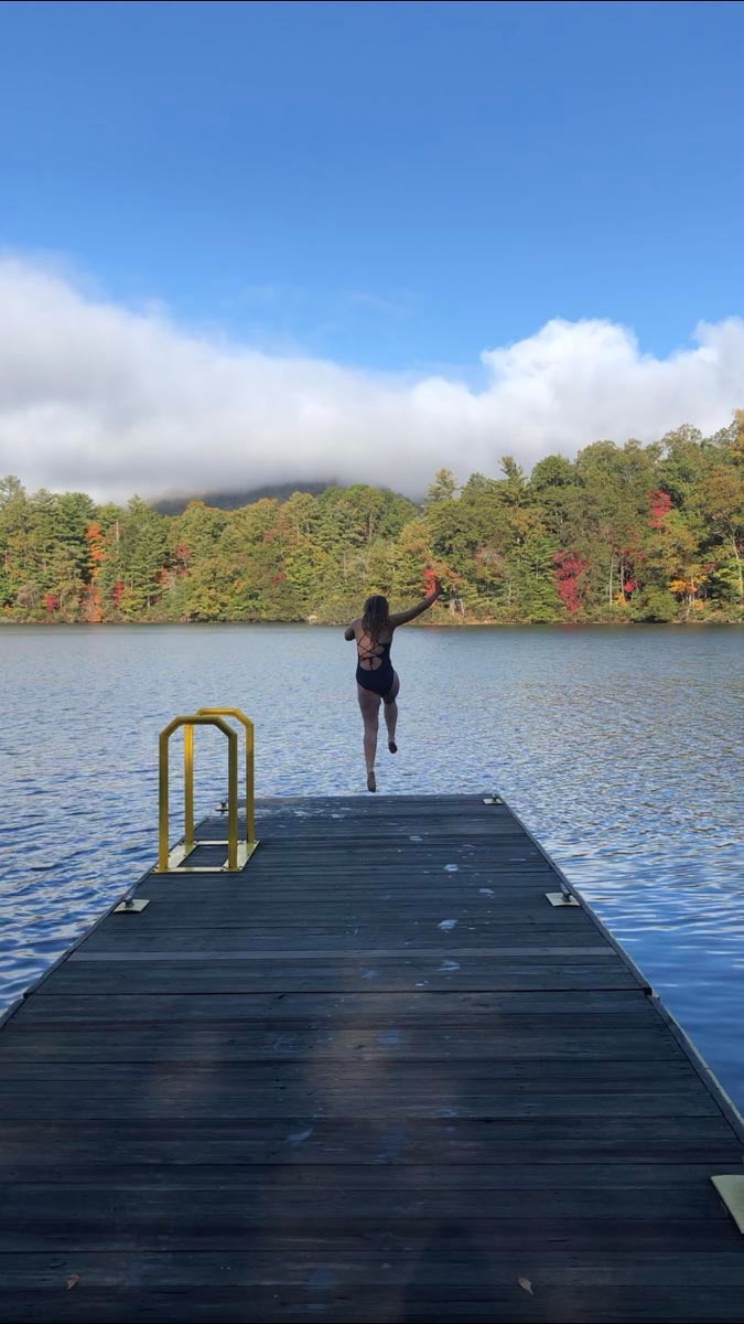 Photo of girl jumping off the edge of a dock into a lake