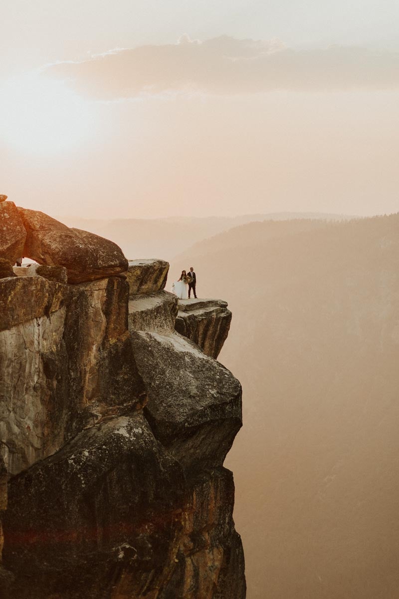 Photo of bride and groom at the edge of a cliff in Yosemite