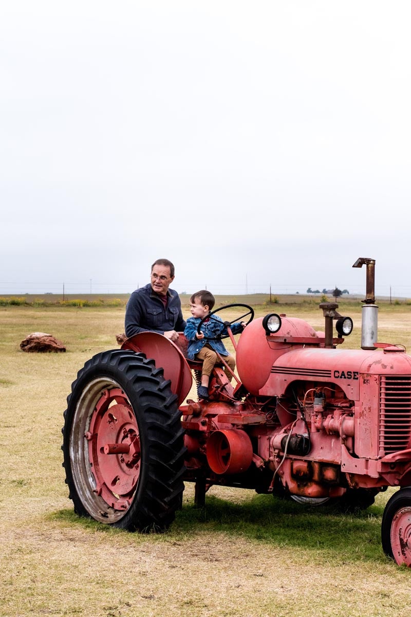 Toddler riding tractor with grandfather