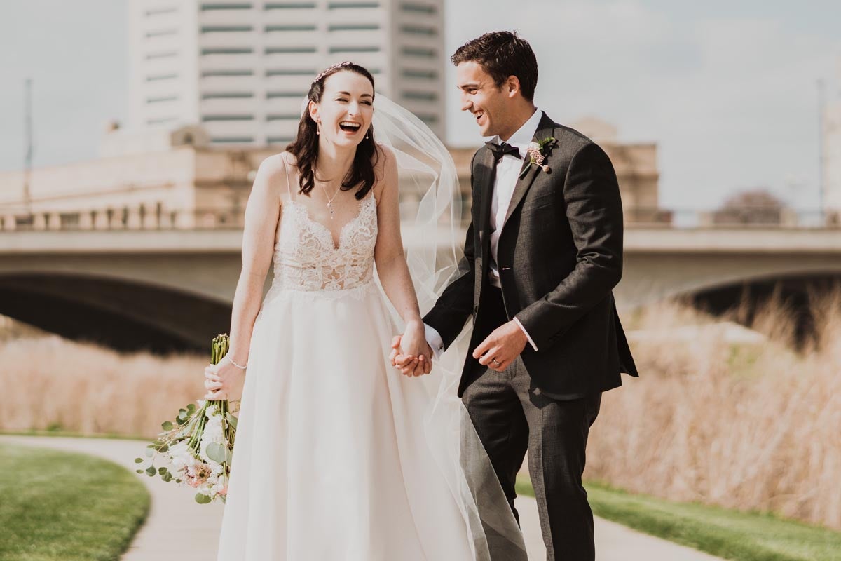 Photo of bride and groom holding hands and laughing