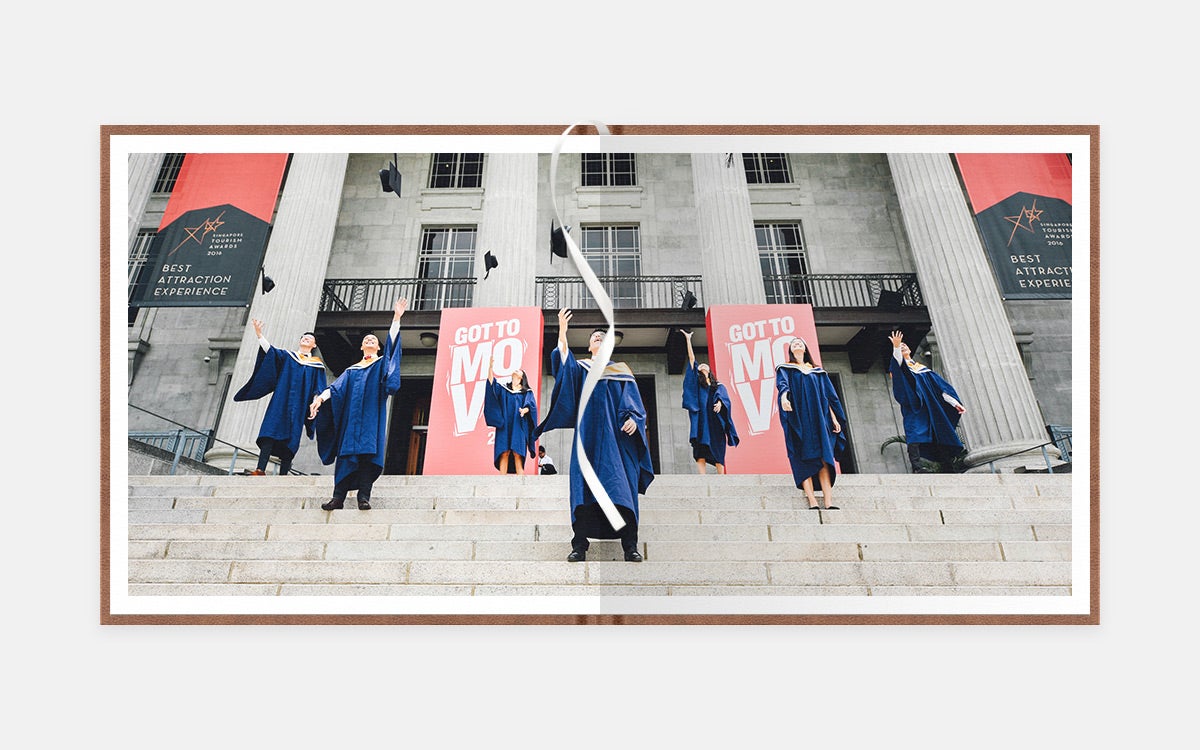 Two-page panoramic image of graduates throwing caps in the air