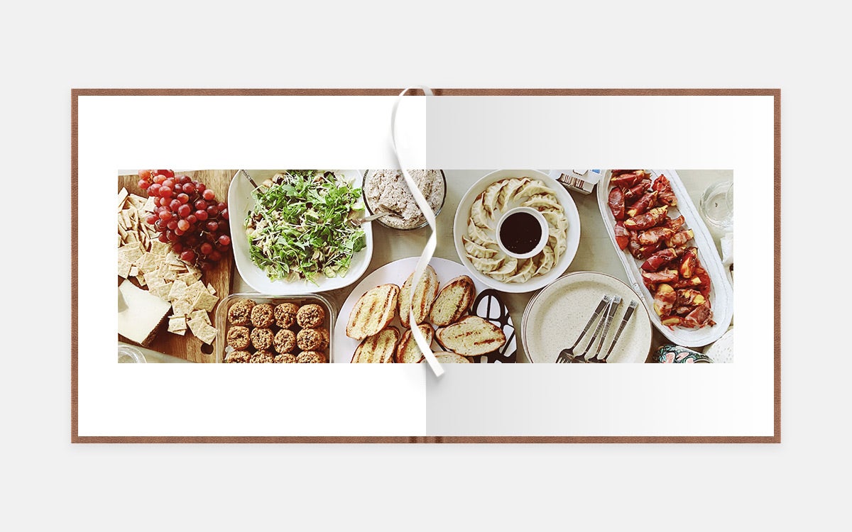 Two-page panoramic album spread of table filled with delicious foods