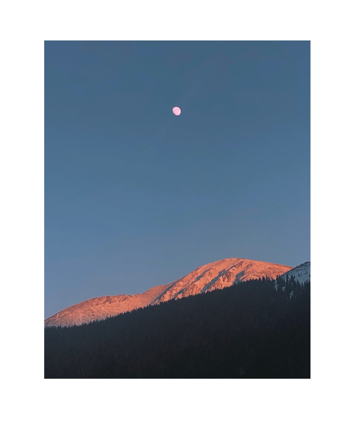 Photo of moon above snow-capped mountains by Molly Olwig