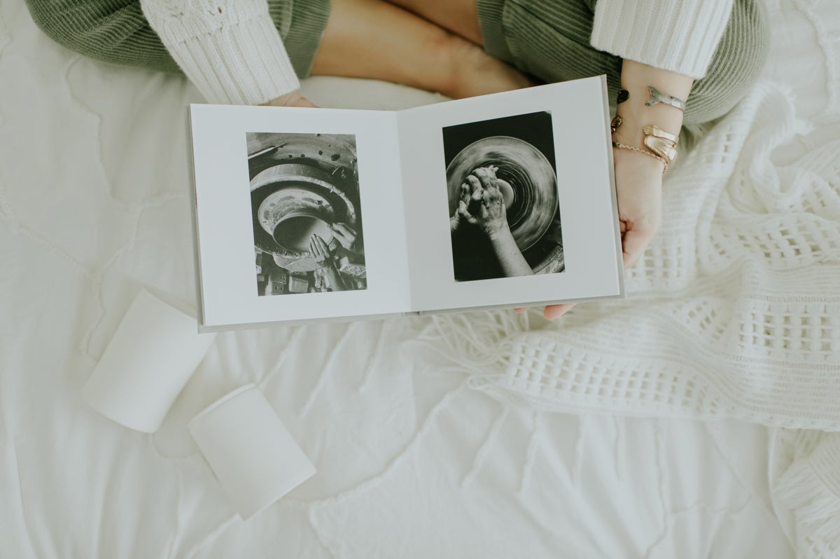 Artifact Uprising Layflat Photo Portfolio Book opened to portrait of young women in long-sleeve striped dress laying in shallow water