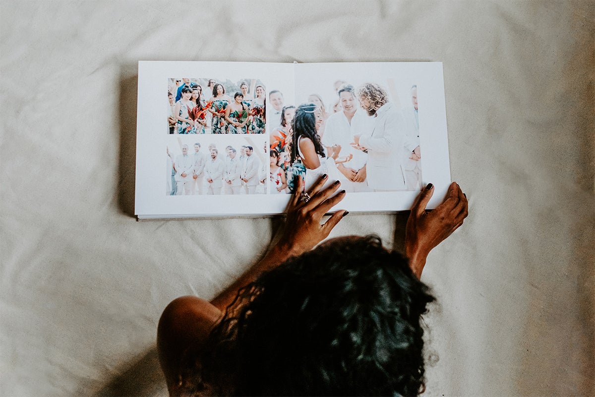 Artifact Uprising Layflat Photo Portfolio Book opened to portrait of young women in long-sleeve striped dress laying in shallow water