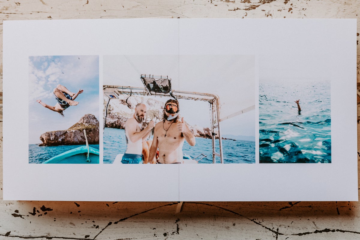 Signature Layflat Album opened to photos of groom and groomsmen on boat