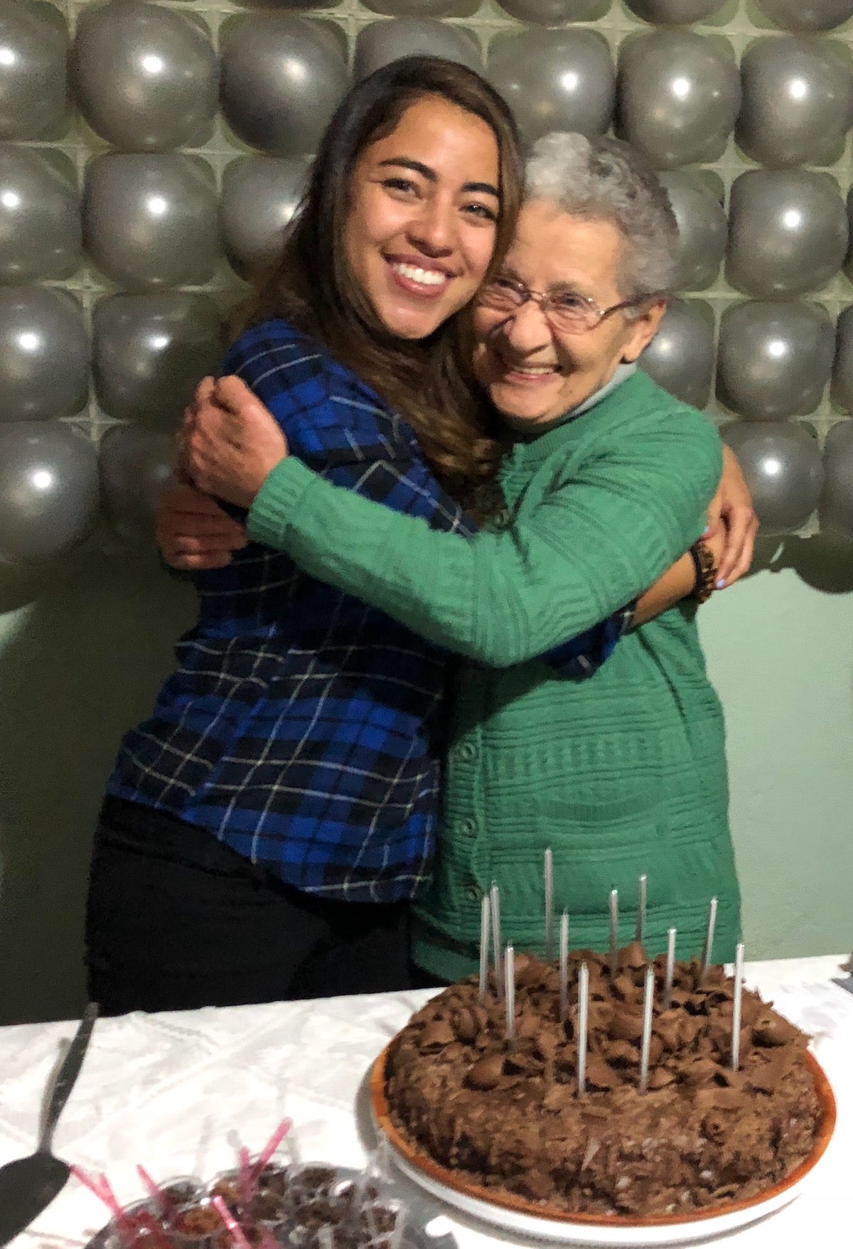 Photo of grandma and granddaughter embracing by birthday cake