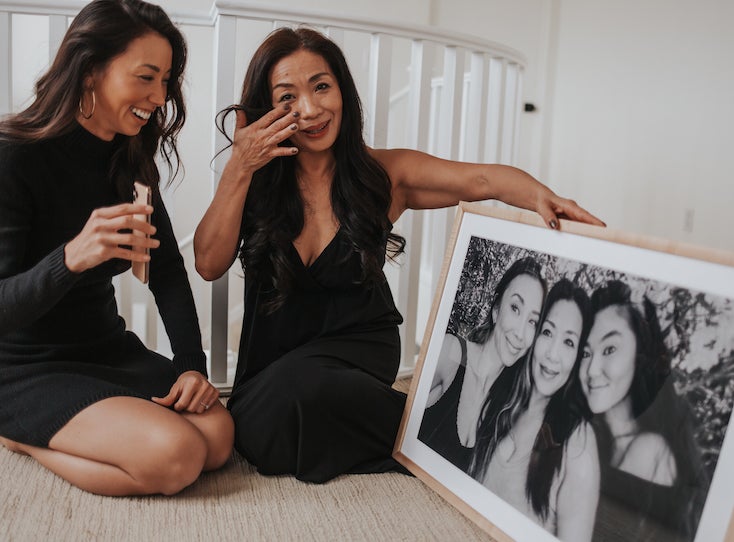 Mom wiping tear from eye as she receives framed photo from daughter