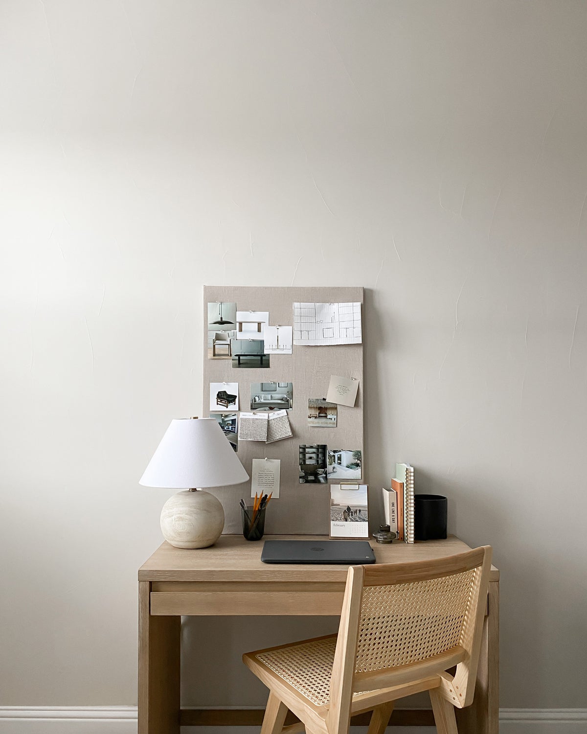 Bulletin board adorned with pictures standing on small desk with wooden chair