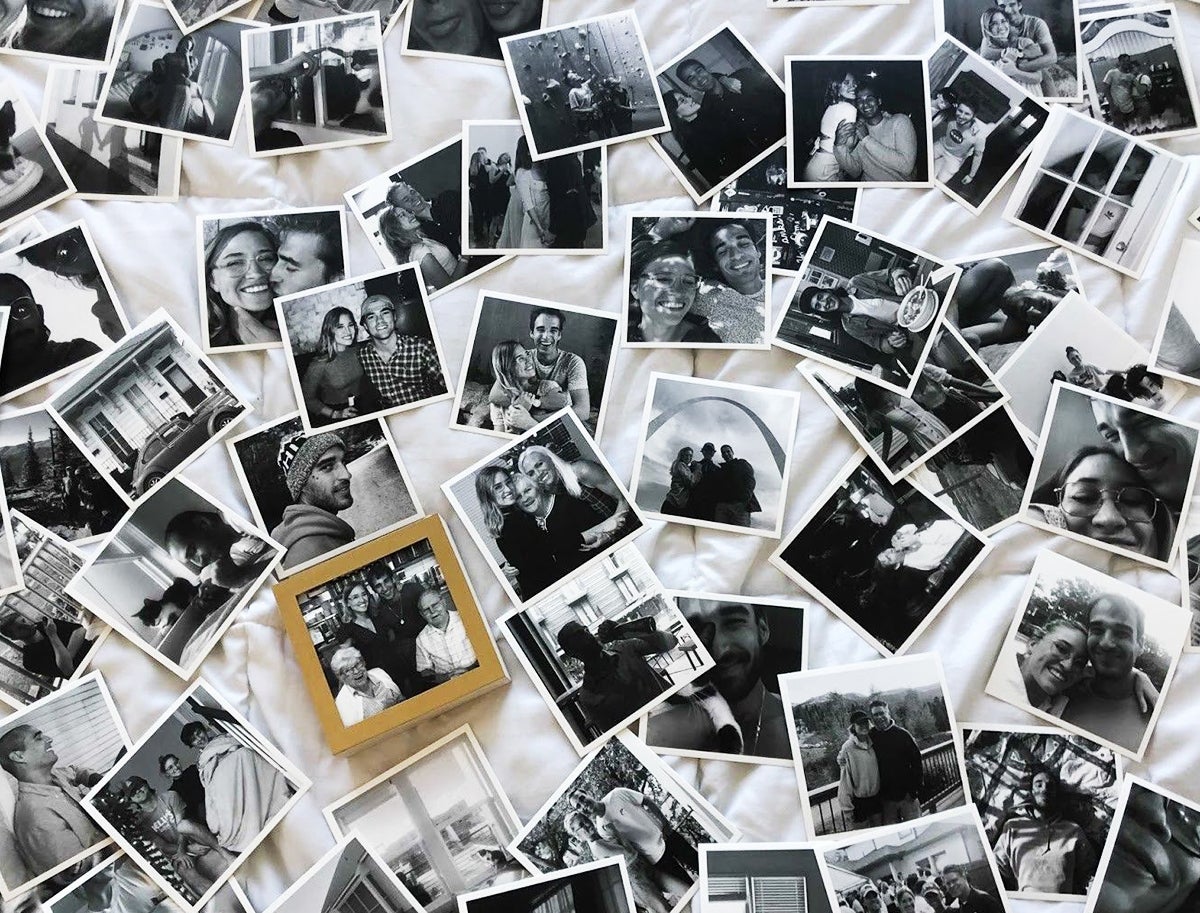 Hundreds of black-and-white Artifact Uprising photo prints scattered on bed