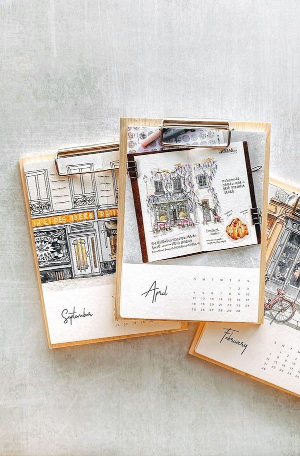 Artifact Uprising Wood Calendar featuring beautiful drawings of travel scenes for every month