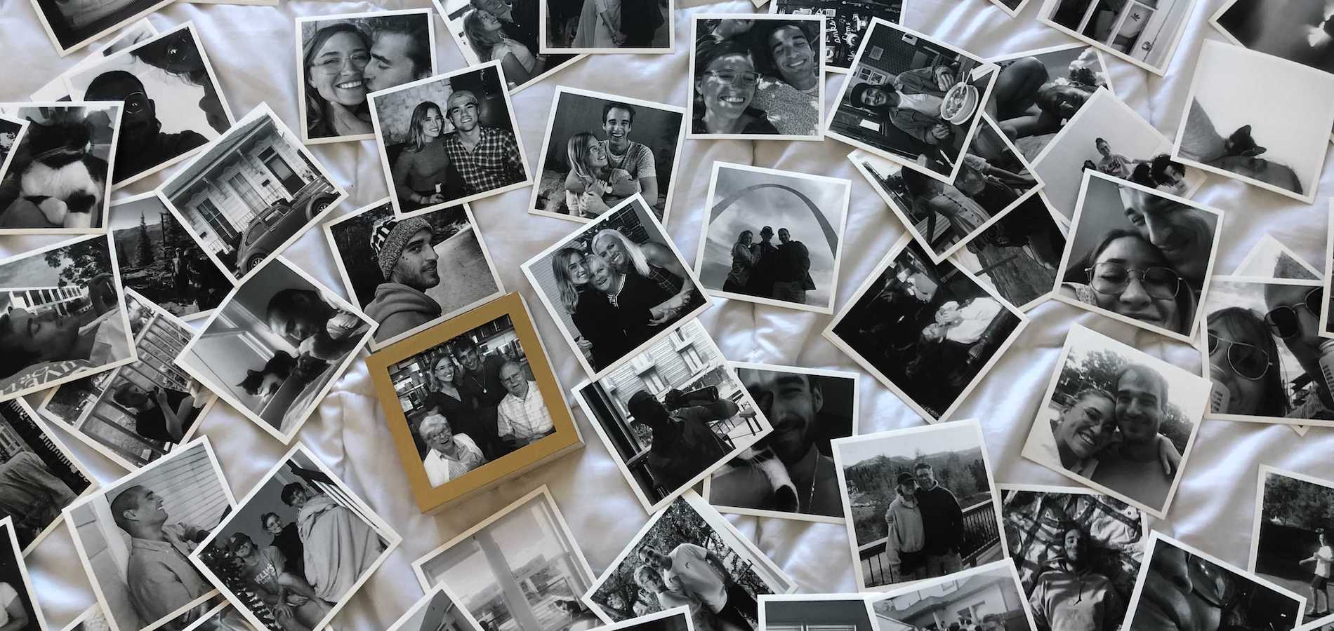 Artifact Uprising photo prints scattered all over bed featuring black-and-white photos