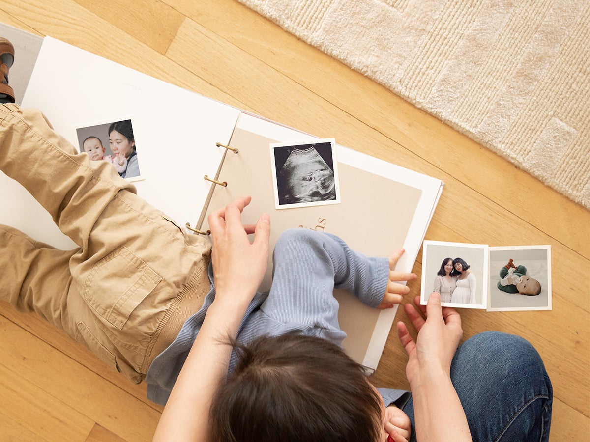 Little lying across Artifact Uprising Story of You Photo Book as mom tries to fill it out