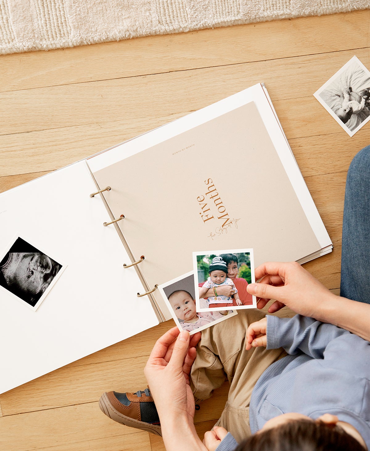 Artifact Uprising Story of You Photo Book opened to month five as mother and little boy choose prints to put inside