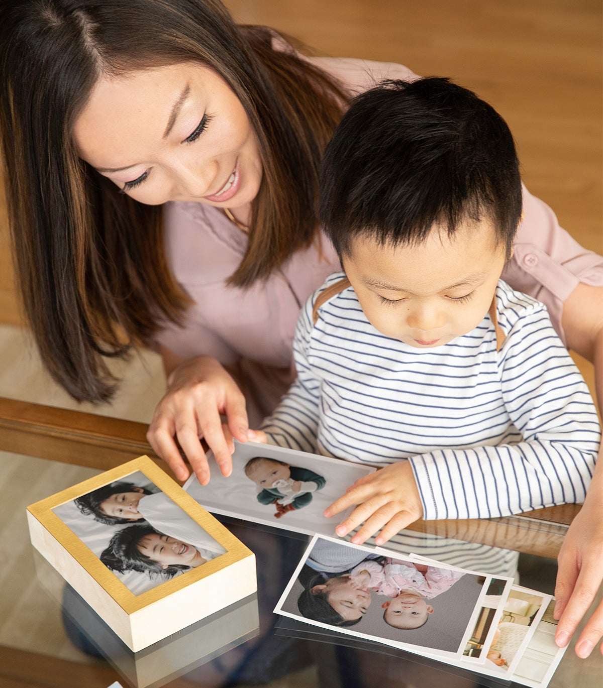 Mom and little boy choosing family photos to place inside Artifact Uprising Brass & Wood Display Box