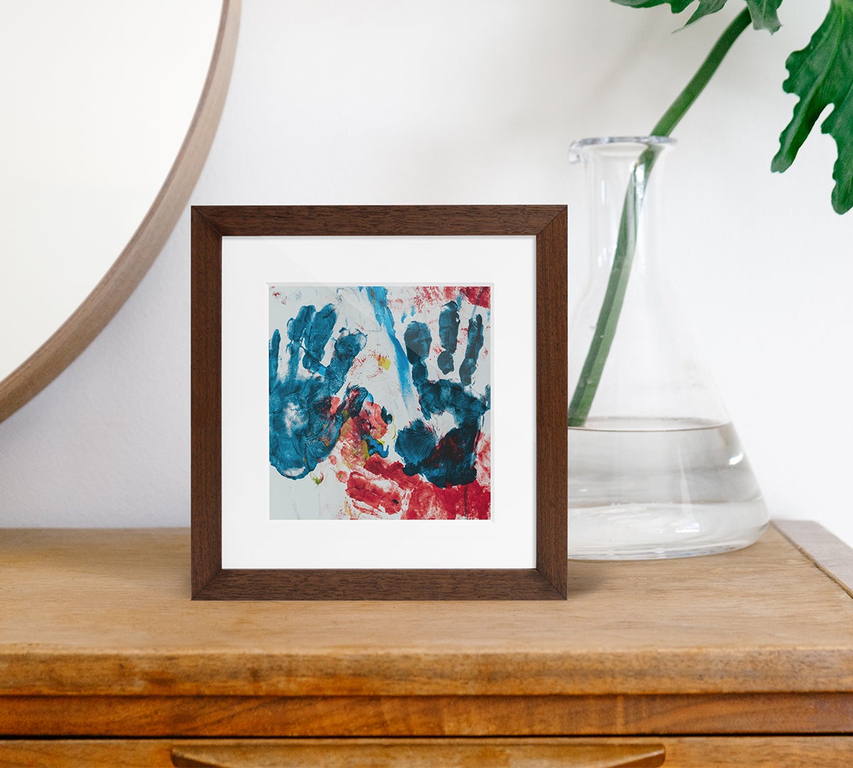 Artifact Uprising Wooden Tabletop frame in walnut finish featuring children's handprints in paint on dresser next to mirror and plant