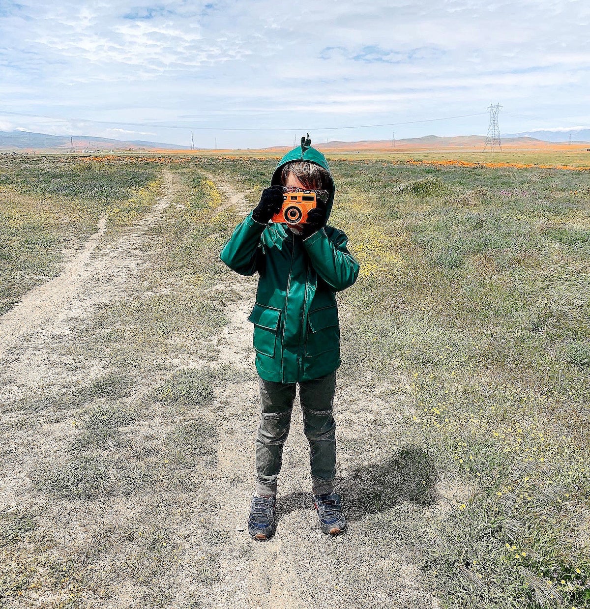 Little boy in field holding up camera