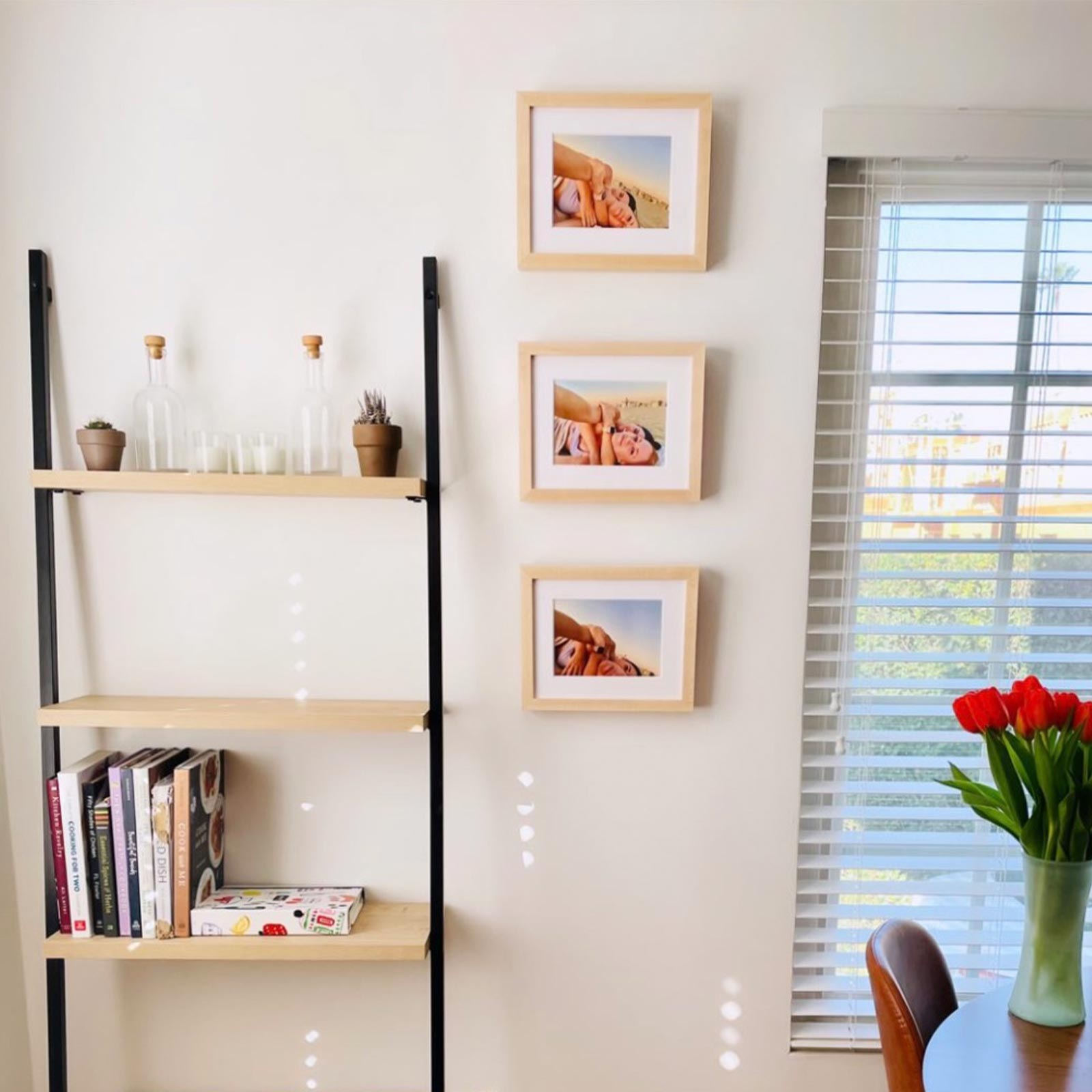  A trio of small wooden Artifact Uprising frames hung one above the other to the left of a window