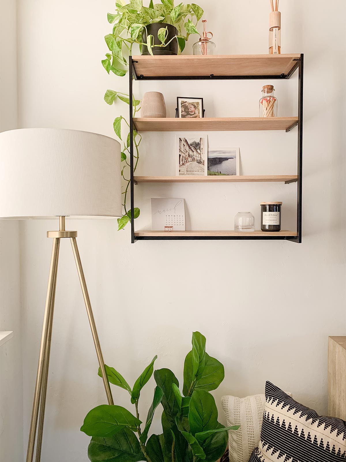 Floating bookshelf lined with Artifact uprising photo prints, decorative items, and a pothos plant