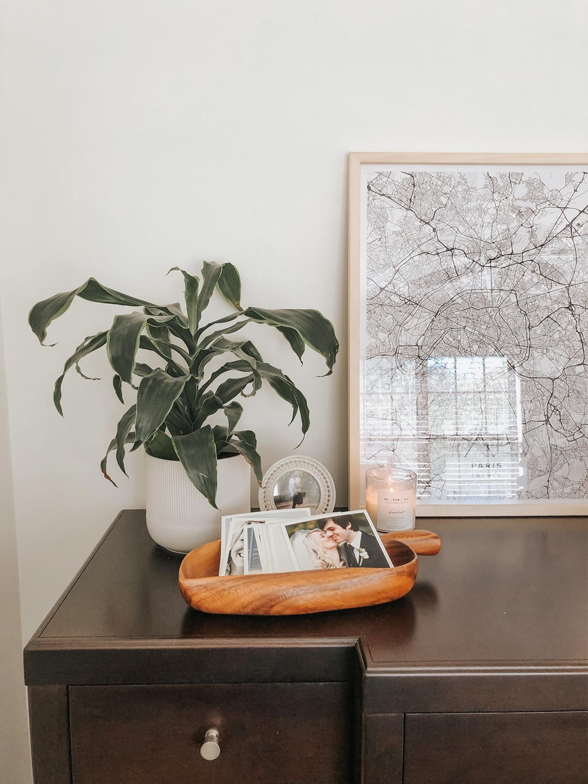 Artifact Uprising Square Prints in decorative wooden bowl on dresser next to plant and large framed photo of snow-covered tree branches